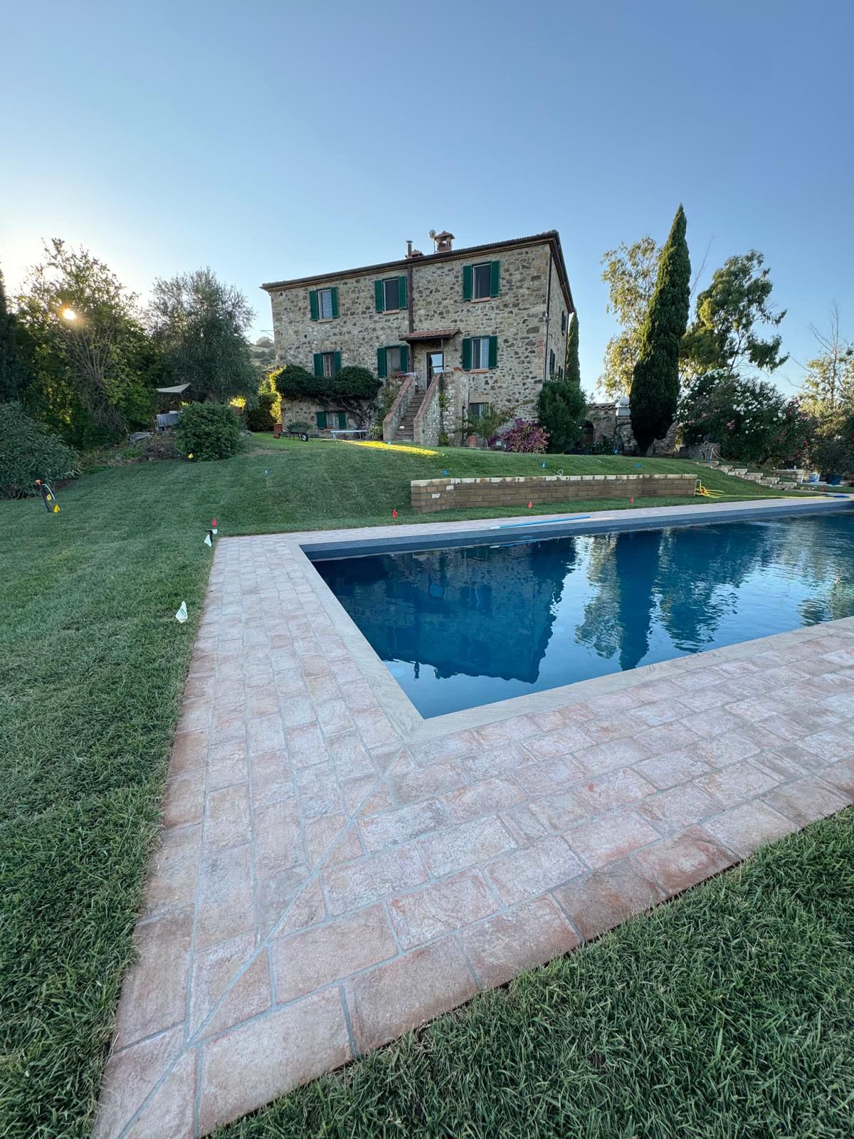 The pool in the evening with the stone house on the rise behind it