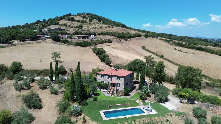 The house set among olive groves and rolling fields, seen from the air