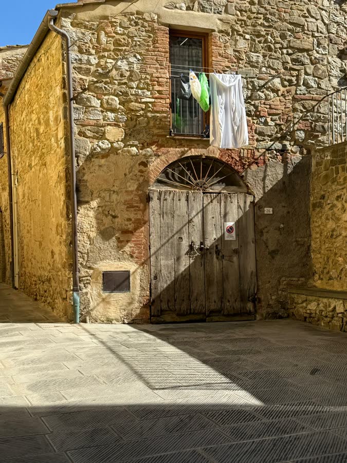 An old stone building with a wooden door and washing hung at the window