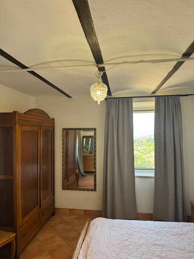 Double bedroom with a wooden wardrobe, a mirror and a beamed ceiling