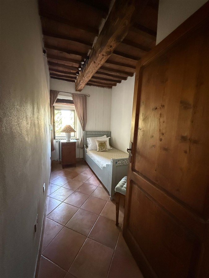 Single bedroom with a grey painted bed beneath an exposed timber ceiling