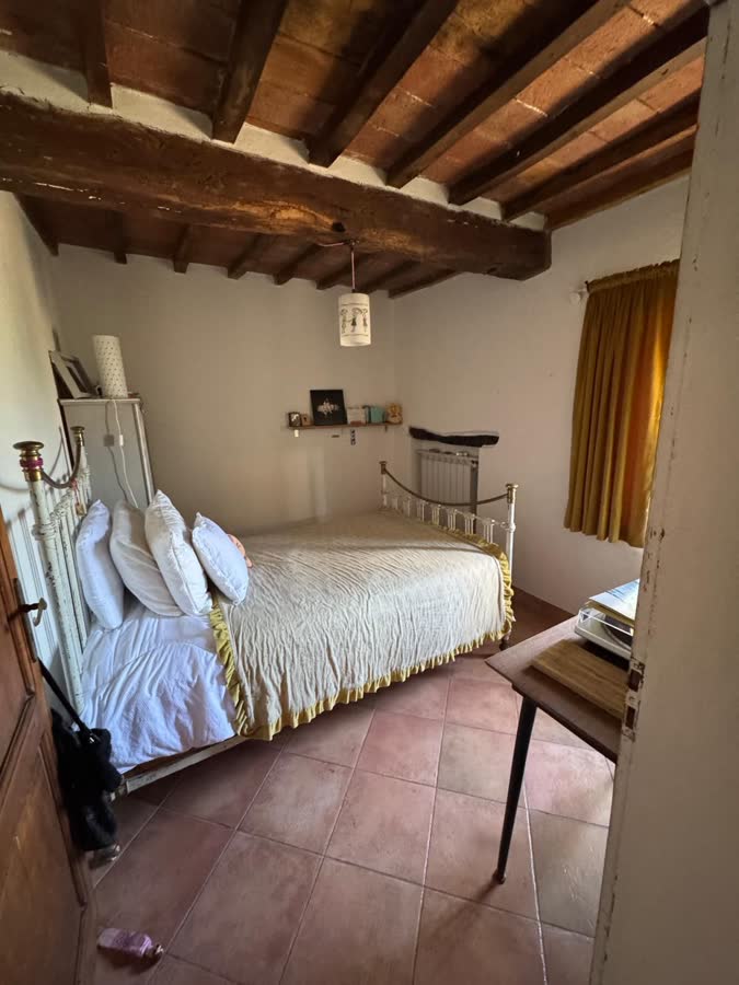 Single bedroom with a white iron bed under a beamed ceiling