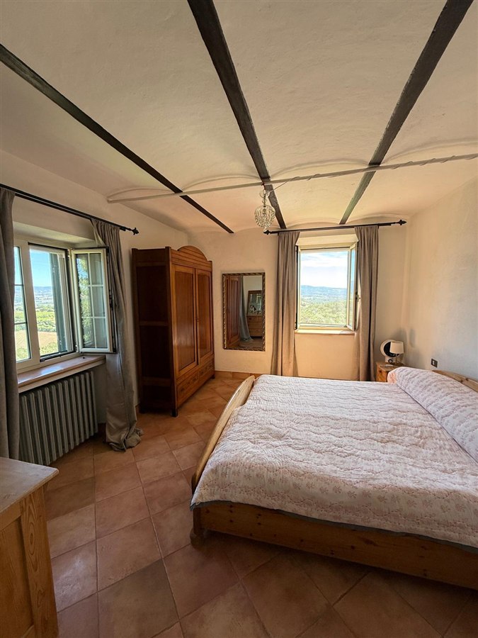 Double bedroom with a wooden bed, beamed ceiling and two windows overlooking the valley