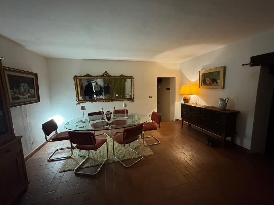 Formal dining room with a glass table, gilt mirror and framed pictures