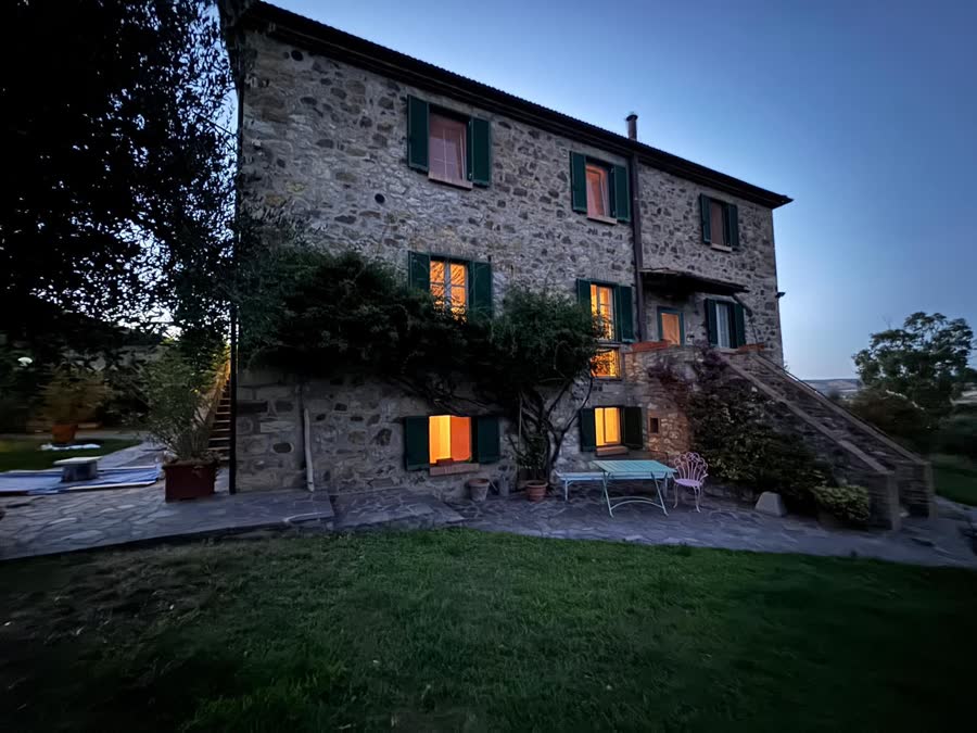 The stone house in the evening with warm light in the windows