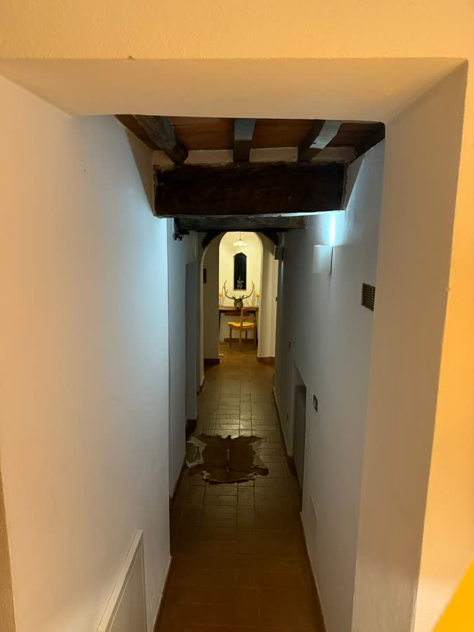 Long hallway with a beamed ceiling and terracotta floor