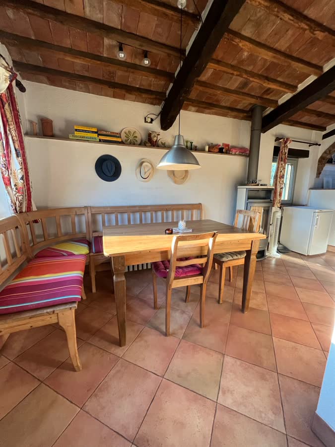 Kitchen and dining room with a long wooden table, striped bench and beamed ceiling