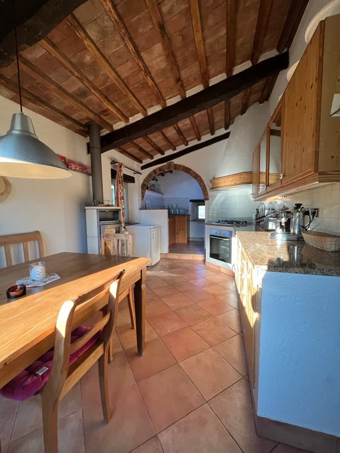 Kitchen with a pendant lamp, wooden table and arch through to the cooking area